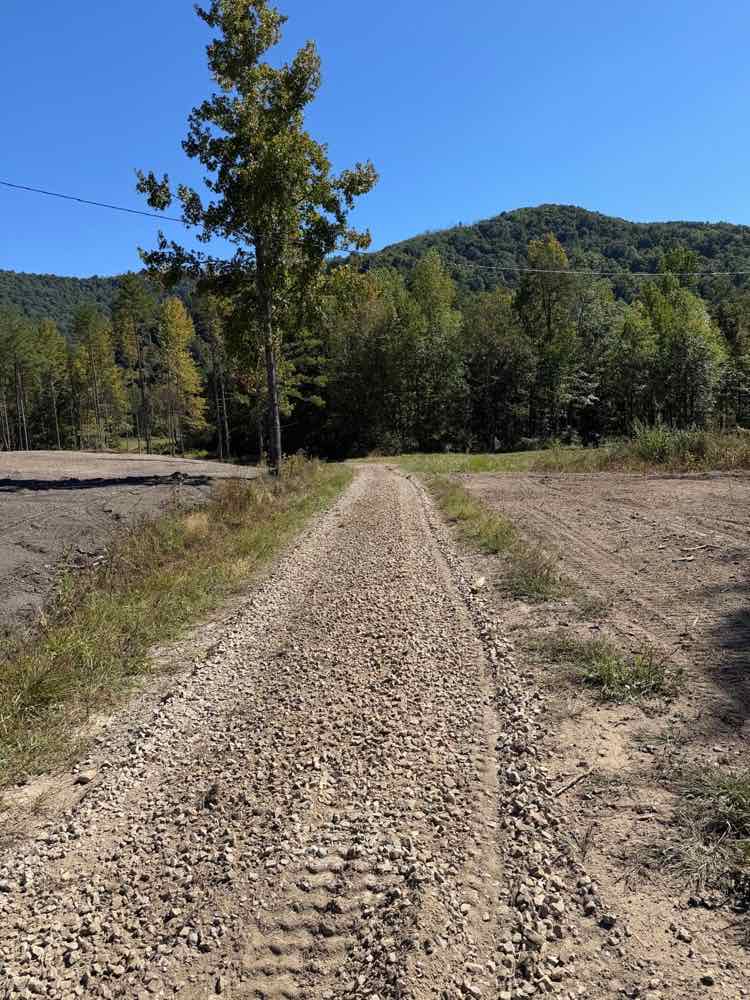 A new crushed-stone gravel drive with graded, cleared ground on both sides